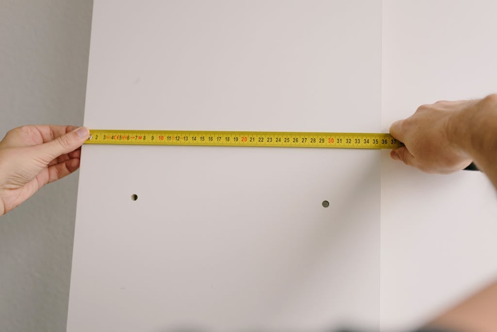 Crop man measuring wooden board in room